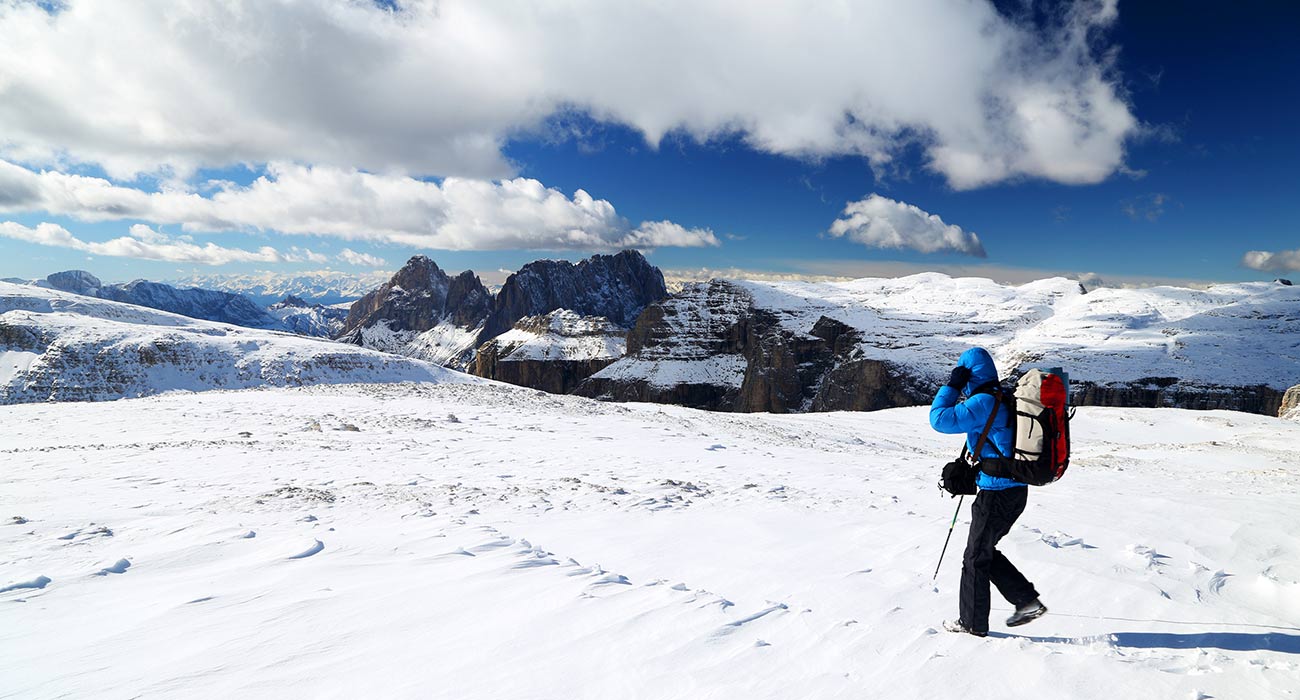 Alpinista con zaino e attrezzatura da montagna durante un'escursione nella neve